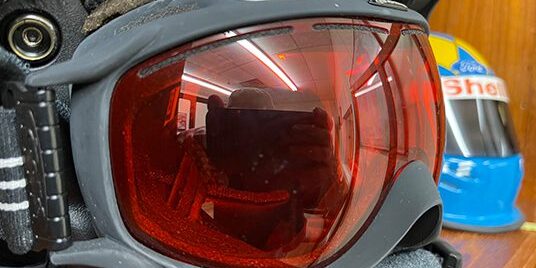 Red-lensed goggles on a wooden surface.